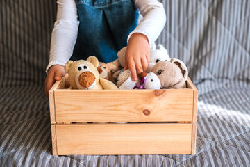 Little girl cleaning up the toy box at home. Child's space organization.