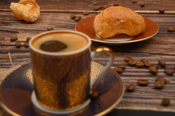 Coffee Cup, croissants and coffee beans on wooden background. Close up.