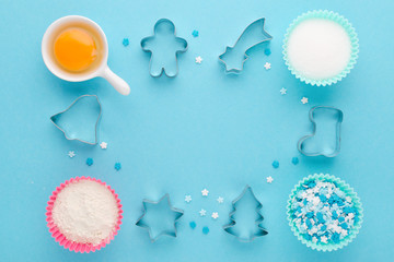 baking ingredients and cookie cutter on blue background, flat lay
