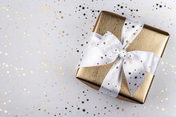 Gold gift box with a white ribbon.