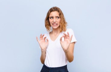 young blonde woman feeling disgusted and nauseous, backing away from something nasty, smelly or...