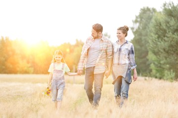 Family walking on grassy field against sky at farm