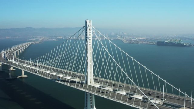 Aerial Shot of Bay Bridge pulling back with Oakland in background as cars commute, San Francisco California