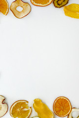 Oranges, apples, kiwis,  mango chips on white background with copy space. Healthy vegan vegetarian fruit snack or ingredient for cooking. Vertical view.