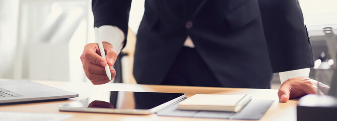 Businessman hands holding digital pen and using tablet with computer at office. proportion of the...