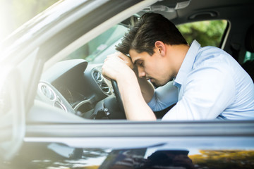 Handsome man tired and sleepy in car feels dangerous