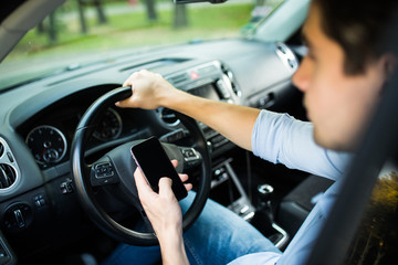 Young man sending a text message in his car