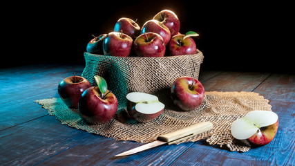 Fresh whole and half cut apples in a bowl on wooded table with knife .