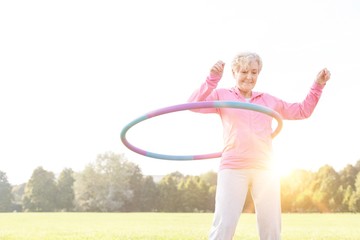 Senior woman doing gymnastic with hula hoop in park © MDBPIXS