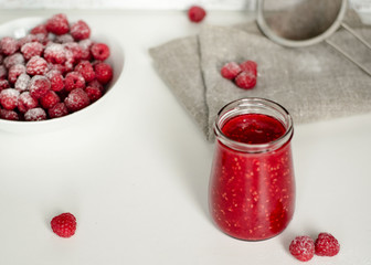 Raspberry and jam with fresh raspberries on the white  wooden table. Marmalade on spoon and jar on wooden background. Rustic style. Close up