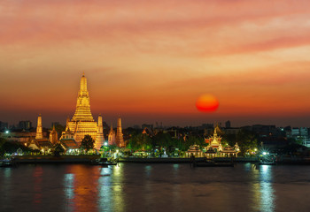 Fototapeta premium Wat Arun Ratchawararam Ratchawaramahawihan or Wat Arun meaning Temple of Dawn on Chao Phraya River at sunset , Bangkok , Thailand