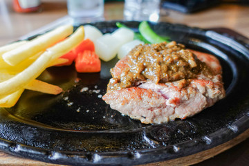 closeup grilled tenderloin steak on hot black metal plate