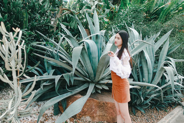 Young beautiful asian woman in white dress posting with cactus and succulent plants  background