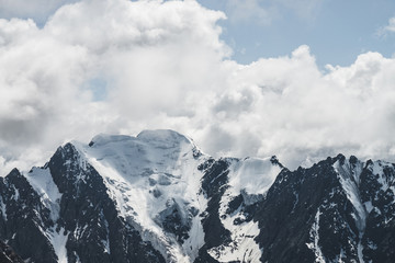 Atmospheric minimalist alpine landscape with massive hanging glacier on snowy mountain peak. Big balcony serac on glacial edge. Cloudy sky over snowbound mountains. Majestic scenery on high altitude.
