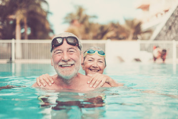 two seniors at the pool hugged together and playing - happy mature people and couple of pensioners...