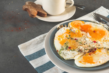 scrambled eggs with thyme and spices on a plate, a Cup of coffee with a gingerbread man on a saucer on a gray background