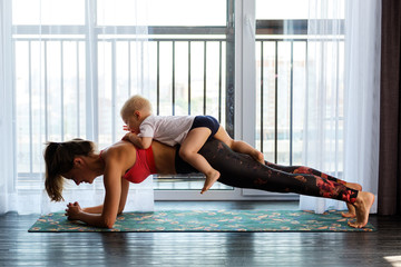 Young mother practices yoga at home with her baby