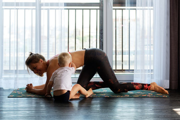 Young mother practices yoga at home with her baby