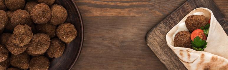 top view of falafel with vegetables and sauce in pita on wooden table, panoramic shot