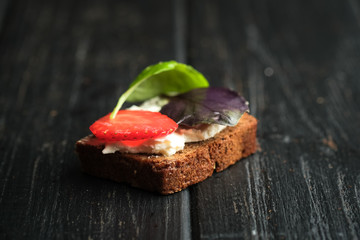Toast or sandwich with avocado, cheese, strawberries, herbs and seeds on a dark background. An idea for bruschetta or for a healthy snack. Healthy vegan breakfast.