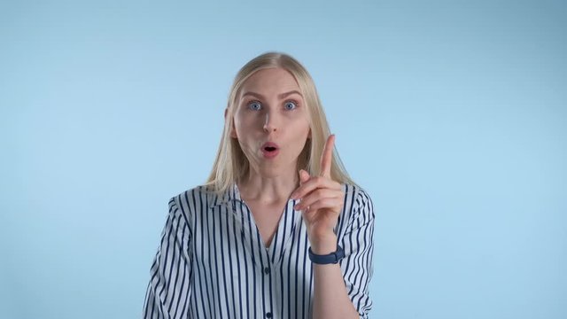 Intelligent young woman suddenly comes to an excellent idea. Blue background.