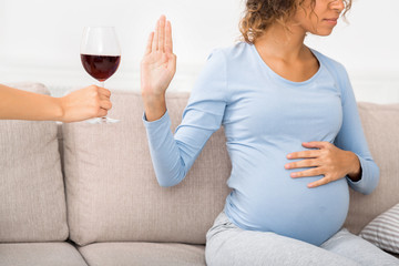 Pregnant woman refusing glass of wine, crop