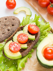 Healthy food. Avocado Sandwich. Rye bread with bran, Cherry Tomatoes, Avocado,Lettuce and Sesame Seed 