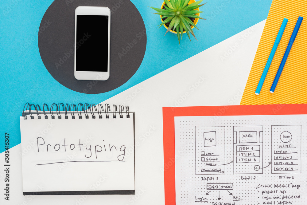 Wall mural top view of smartphone near website design template and notebook with prototyping lettering on abstr
