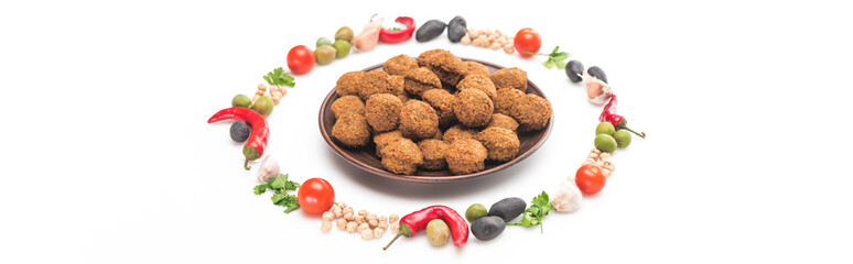 chickpea, garlic, cherry tomatoes, parsley, olives, chili pepper, green onion arranged in round frame around falafel balls on plate on white background, panoramic shot
