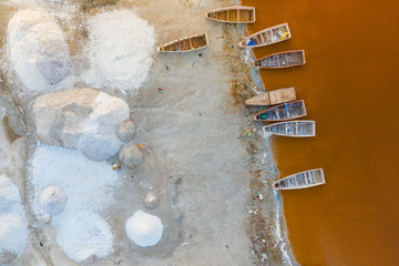 Aerial view of the small boats for salt collecting at pink Lake Retba or Lac Rose in Senegal. Photo made by drone from above. Africa Natural Landscape.