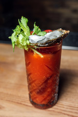 Bloody mary cocktail with an oyster decoration on a bar counter