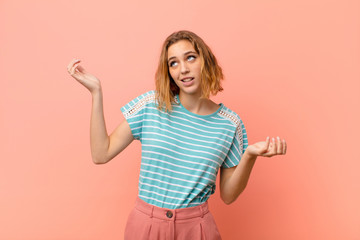 young blonde woman shrugging with a dumb, crazy, confused, puzzled expression, feeling annoyed and...