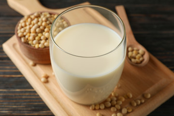 Glass of soy milk and soybeans seeds on wooden background, space for text. Closeup