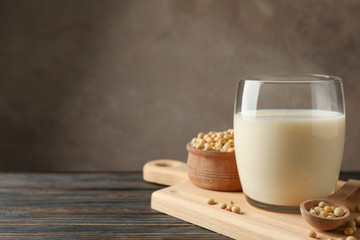 Glass of soy milk and soybeans seeds on wooden background, space for text