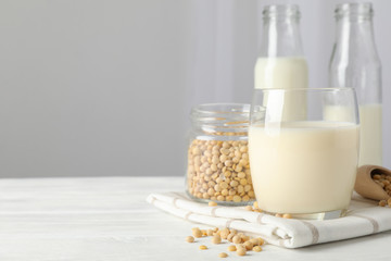 Glass of soy milk, soybeats seeds, bottle with milk on white background, space for text