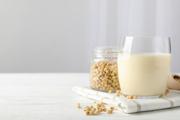 Glass of soy milk, soybeats seeds on white background, space for text. Closeup