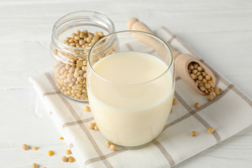 Glass of soy milk, soybeats seeds on white background, space for text. Closeup