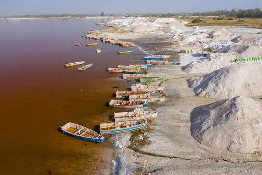 Aerial view of the small boats for salt collecting at pink Lake Retba or Lac Rose in Senegal. Photo made by drone from above. Africa Natural Landscape.