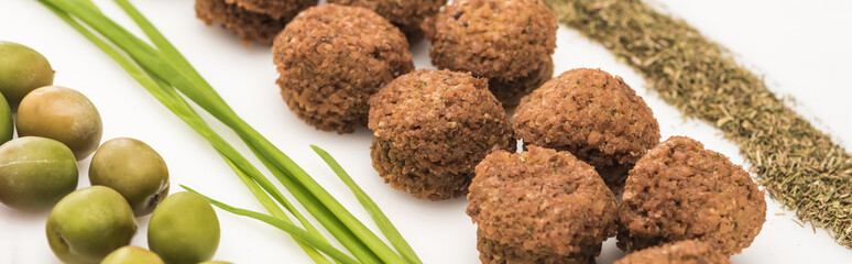 close up view of olives, green onion, herb and falafel on white background, panoramic shot