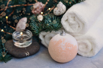 Christmas and new year Spa concept with fir branches decorated with lights, shells, stones and bath bomb on grey backgraund