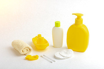 Mock up of baby bath products: bottles for shampoo (shower gel, lotion, oil), towel, cotton buds and pads on white background. Close up, copy space for text. Concept of baby bath accessories