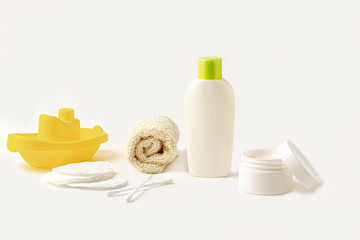 Mock up of baby bath products: bottles for shampoo (shower gel, lotion, oil), towel, cotton buds and pads on white background. Close up, copy space for text. Concept of baby bath accessories