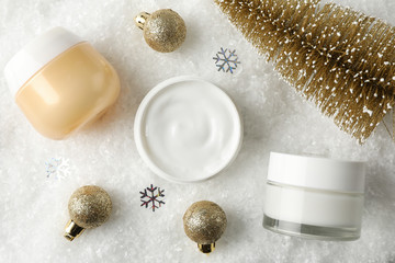 Fototapeta na wymiar Jar of winter cream for skin, christmas tree and toy on snowy background, space for text. Top view