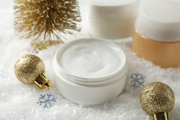 Fototapeta na wymiar Jar of winter cream for skin, christmas tree and toy on snowy background, space for text. Closeup