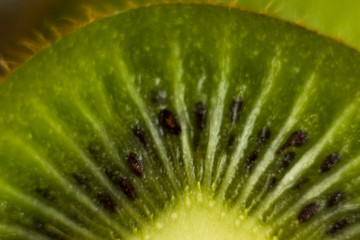 Closeup of a kiwi on the wooden background. Cut piece of kiwi fruit with skin on a wooden table