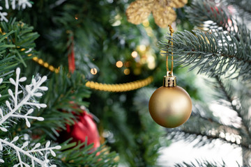 Gold ball hanging from a decorated Christmas tree.