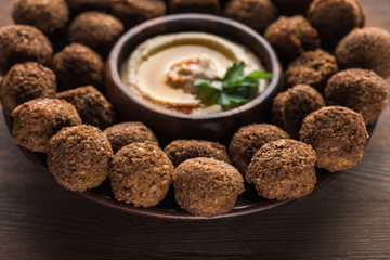 close up view of falafel balls with hummus on plate on wooden table