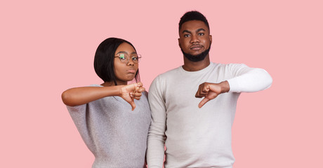 Afro couple showing thumb down gesture as rejection symbol