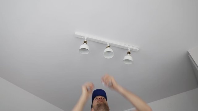 electrician installing led light bulbs in ceiling lamp