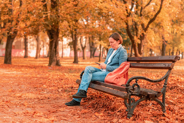 Businesswoman typing text message on mobile phone on park bench